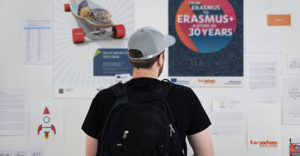young man stands in front of an information board about EU projects