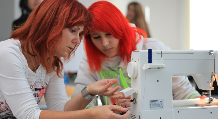Instructor shows a student the handling of a sewing machine