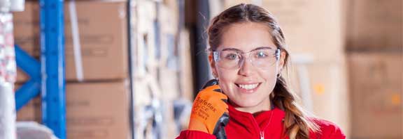 Young woman with safety glasses and safety gloves in a warehouse