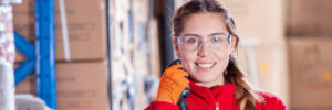 Young woman with safety glasses and safety gloves in a warehouse