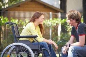 a girl in a wheelchair talking to a boy in the park