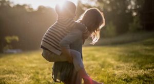 Student on a meadow carrying a child on her back